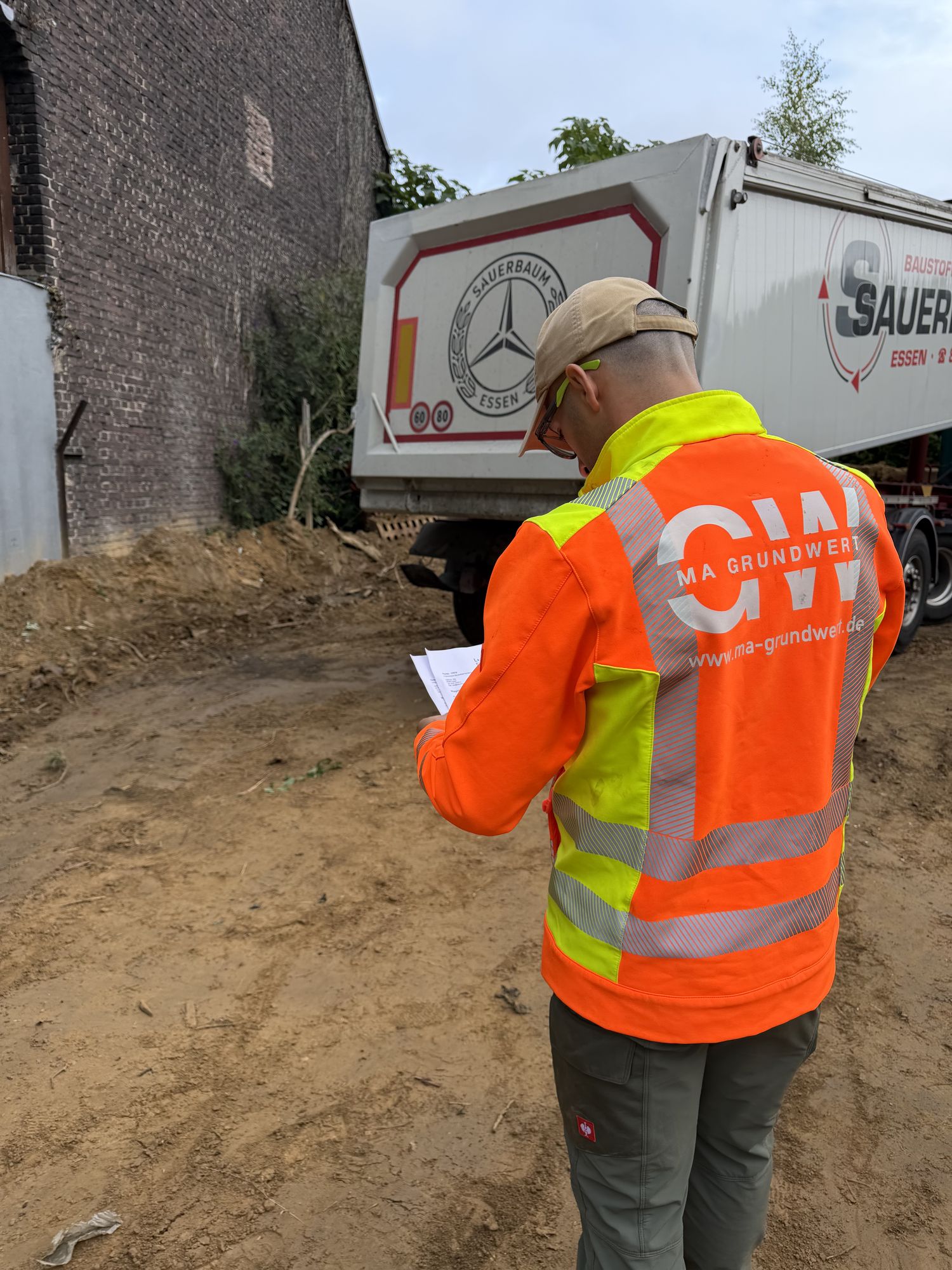 MA Grundwert Mitarbeiter mit Bauplan und Baustoff-Lieferung auf einer Infrastruktur-Baustelle – Generalunternehmer für Tief- und Straßenbau
